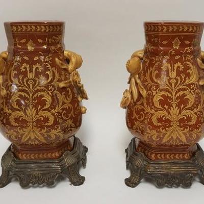 1073	PAIR OF DECORATIVE CERAMIC VASES ON BRASS BASES, RELIEF ROSE HANDLES, 15 IN TOTAL HEIGHT, CHIPS ON ONE HANDLE
