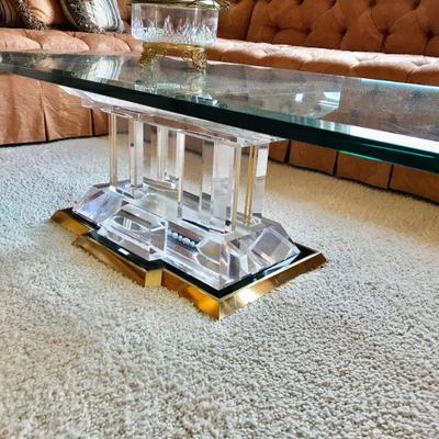 Glass top coffee table, raised on a lucite shaped base with four supports with brass trim. L56x W27' x 15 1/2