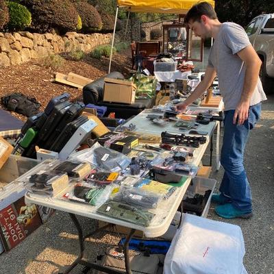 Crew member sorting the dozens of brand new gun accessories like scopes laser sights and flash lights and brand new holsters - from...