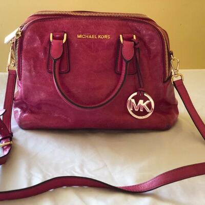 Michael Kors fucshia patent leather purse with handles and a shoulder strap. 