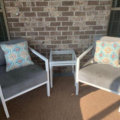 Outdoor furniture to included two chairs, a table and throw pillows.