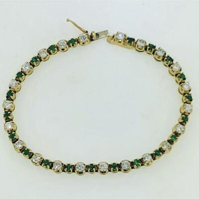 One 14kt gold emerald & diamond tennis bracelet. The bracelet alternates between twenty-two (22), four prong set, round brilliant cut...