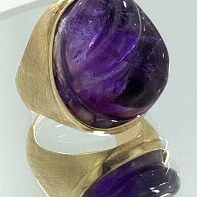 Beautifully carved amethyst ring. The ring features one (1), bezel set, ovalish carved amethyst set in the center set in a gold mounting...