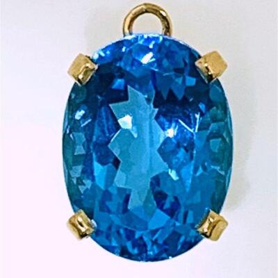 One 14kt gold blue topaz solitaire style pendant. The pendant features one (1), four prong set, oval faceted blue topaz set in a basket...