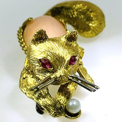 18kt gold coral, ruby & pearl cat design brooch. The brooch features one (1), four prong set, pear cabochon coral set as the body with a...