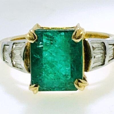 One 14kt two tone gold emerald & diamond ring. The ring features one (1), four prong set, emerald step cut emerald set in the center...