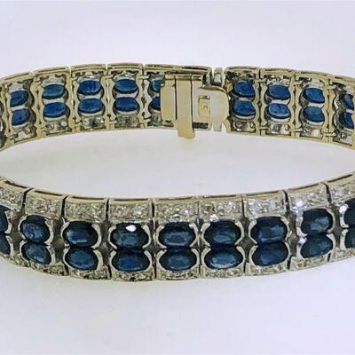 One 18kt white gold sapphire & diamond bracelet. The bracelet has a central double row featuring a total of sixty-eight (68), half bezel...
