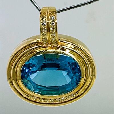 One 14kt gold blue topaz & diamond pendant/ pearl enhancer. The piece features one (1), bezel set oval faceted blue topaz set above nine...