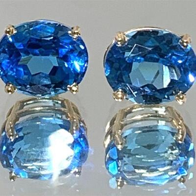 One pair of 14kt gold blue topaz stud style earrings. Each earring features one (1), four prong set, oval faceted blue topaz set in a...