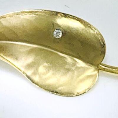14kt gold leaf design diamond brooch. The brooch features one (1), four prong set, round brilliant cut diamond set on the leaf which...