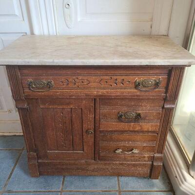 https://ctbids.com/#!/description/share/679244 Marble top on wood table/cabinet. Has three drawers and a cabinet for storage. Top drawer...