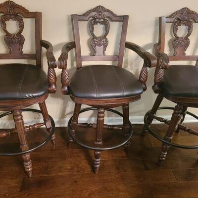 Three beautiful barstools from Ashley Furniture North Shore collection. Barstools have faux leather seats with ornate carved wooden back...