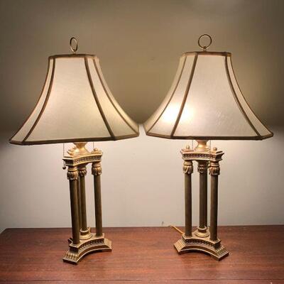 A matching set of brass lamps. Both lamps have dual fixtures and have working brass pull chains. They feature decorative columns that...