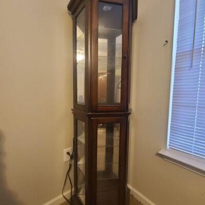 Cherry finish hexagon lighted curio has two cabinet doors though is one full piece, does not come apart. Glass shelving can be removed...