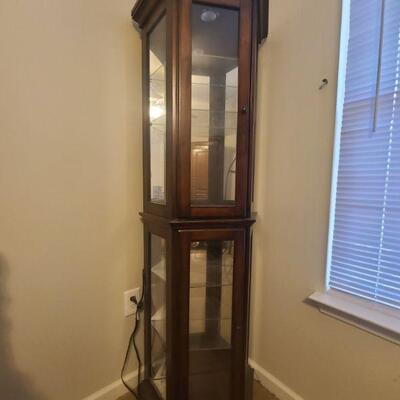 Cherry finish hexagon lighted curio has two cabinet doors though is one full piece, does not come apart. Glass shelving can be removed...