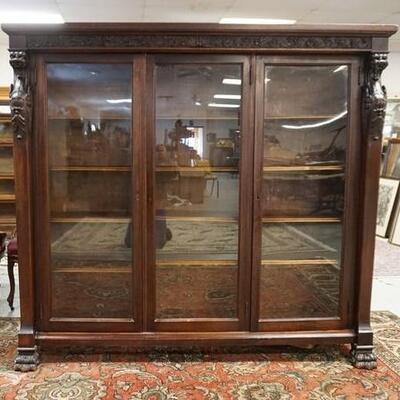 1009	CARVED HORNER MAHOGANY 3 DOOR BOOKCASE, HAS GRAIN CARVING & CLAW FEET & LEAF & SCROLL BAND ACROSS THE TOP, ONE GLASS DOOR HAS BEEN...