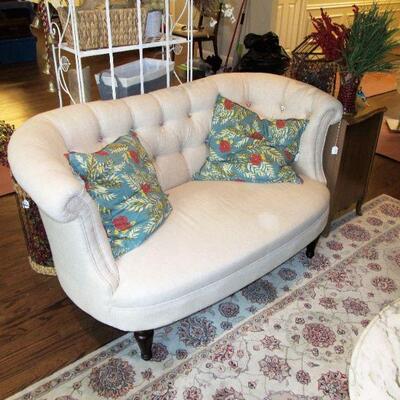 A lovely curved back tufted sofa in a neutral fabric with color fabric buttons.