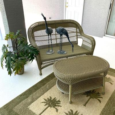 Outdoor wicker loveseat and coffee table pictured with palm print rug. Loveseat measures 55