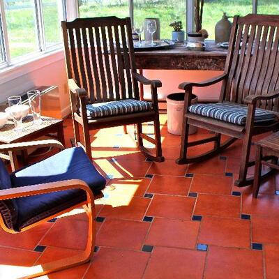 Pair of teak rocking chairs with Sunbrella cushions, Ikea wood frame chair, teak side tables, tall rustic table.