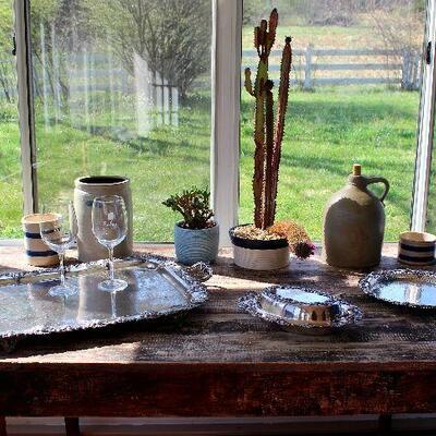 Antique stoneware crocks, silver plate tray and serving pieces with grape motif decoration, rustic table.