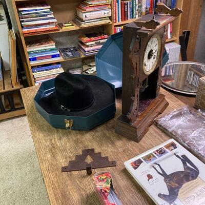 books, cowboy hat in case and a clock needing repair