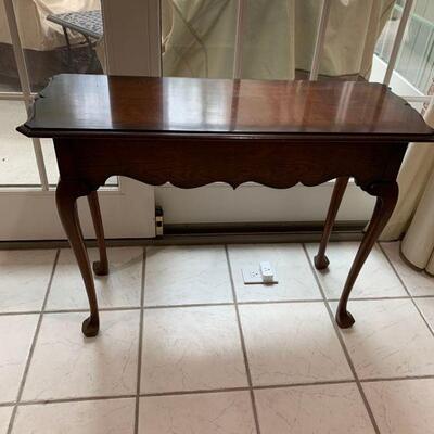 Pretty dark stained entry table with tall legs. It has a design on the ends of the table as well as the bottom of the table....