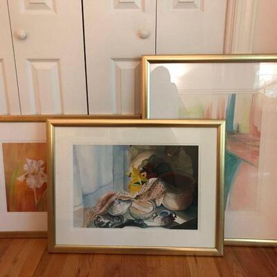 Set of three pictures with gold frames. The Art are floral themed. Flowers and makeup measures- 26â€ x 34â€ iris print measures- 30â€...