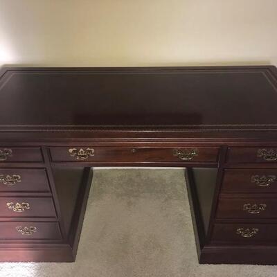 Sligh wood desk with gold details and handles. It has seven drawers and measures 26â€ x 56â€ x 30â€.