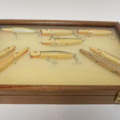 1223	GROUP OF 9 JOHN HENRIKSEN PLUGS FISHING LURES IN A WALNUT DISPLAY CASE, 12 IN X 18 IN X 2 1/2 IN 
