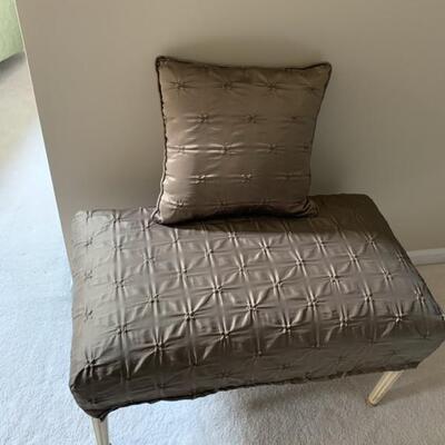 bench covered in brown fabric and accent pillow