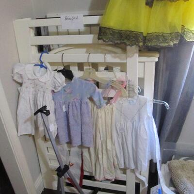 Several cute vintage girl's dresses, white baby crib.