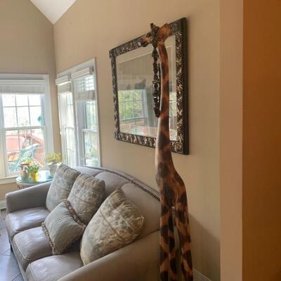 All leather couch with matching chair and a wooden giraffe to complete a cute setting