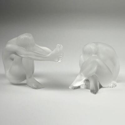 Lot of two Lalique crystal figures from the yoga pose series. Includes â€œNu Nabhiâ€, a woman in seated position with head between her...