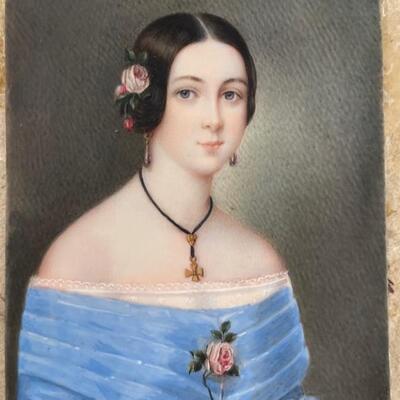"Unsigned miniature hand painted portrait of a young woman in blue dress and with cross necklace. Traveling leather case. Frame is...