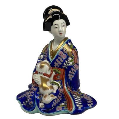 "Japanese porcelain seated geisha wearing a vibrant blue robe with multicolor enamel foliage and gold accents. Playful dog upon her...