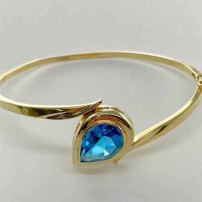 A 14kt yellow gold bracelet with pear shaped blue topaz. Clasp closure with safety clasp. Cuff slightly bent (see photos). 2 5/8â€ wide,...