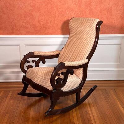 MAHOGANY ROCKING CHAIR | Antique rocking chair with a carved wood frame, upholstered seat, backrest, and arm rests; h. 39 x w. 19 x d. 37...