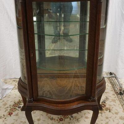 1061	DIMINUTIVE OAK CURIO CABINET WITH CURVED FRONT GLASS DOOR AND SERPENTINE GLASS SIDES.HAVING FULL COLUMNS ON FRONT. APPROXIMATELY 34...