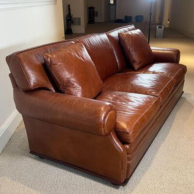 RALPH LAUREN LEATHER SOFA | Brown leather sofa, three cushions with two accent pillows, on a lower wood trim [appearing in overall very...