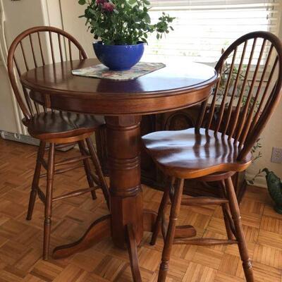 Solid wood bar table with two swivel chairs. 36” diameter and 42” tall.