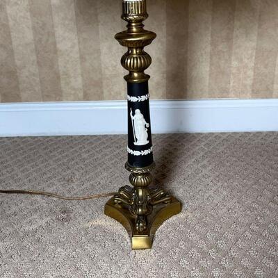 GREEK-STYLE TABLE LAMP | Brass tripod base supporting a black column with white raised laurel leaves and the figure of a woman holding a...