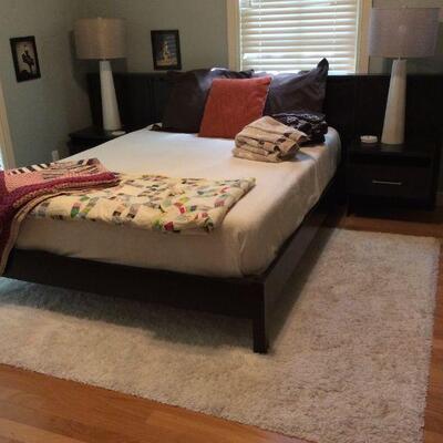 Black queen bed with attached nightstands and cool lamps