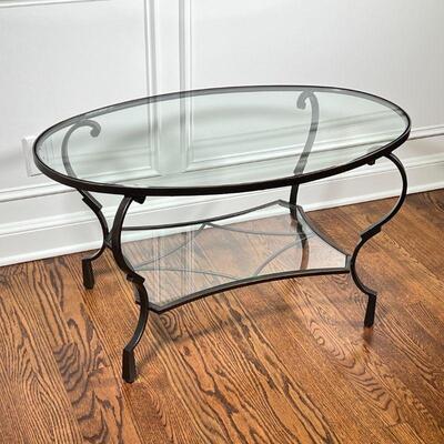 METAL & GLASS LOW TABLE | Low side table having a bronze-toned metal frame with an oval glass top and medial shelf; h. 20 x 36 x 22 in.
