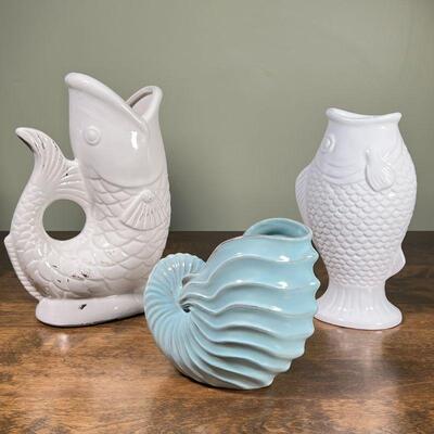 (3pc) NAUTICAL CERAMICS | Including two white fish-form vases, one designed as a pitcher (tallest 13 in.) and a nautilus-form blue vase