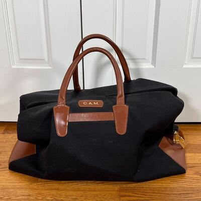 T. ANTHONY DUFFLE BAG | Black canvas bag with brown leather straps and full leather bottom, monogrammed C.A.M.; approx. 13 x 23 x 11 in.