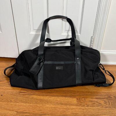 KENNETH COLE DUFFLE BAG | Black duffle bag with leather straps and accents, appearing in very good condition; approx. 8 x 25 x 15 in.