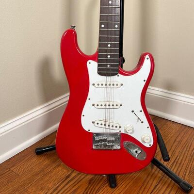 FENDER SQUIER ELECTRIC GUITAR | Red and white guitar on an On-Stage Stand (guitar h. 34-1/2 in.) [missing a few strings, can be cleaned]