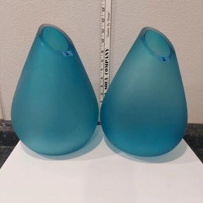 a pair of thick, aquamarine colored glass vases