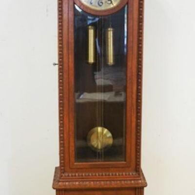 1002	OAK GRANDFATHERS CLOCK W/ARCHED TOP, CARVED CREST, BEVELED GLASS DOOR AND BRASS FACE, APPROXIMATELY 22 IN X 12 IN X 82 IN HIGH
