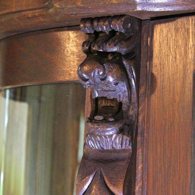 Detail - carved lion faces flank the cabinet door.